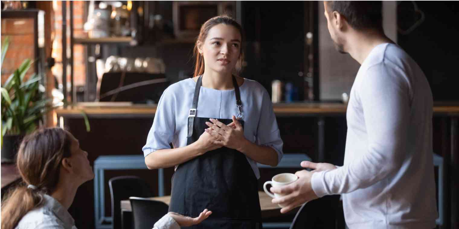 A screenshot of a woman who works at a coffee shop, talking to a customer who appears to be disappointed