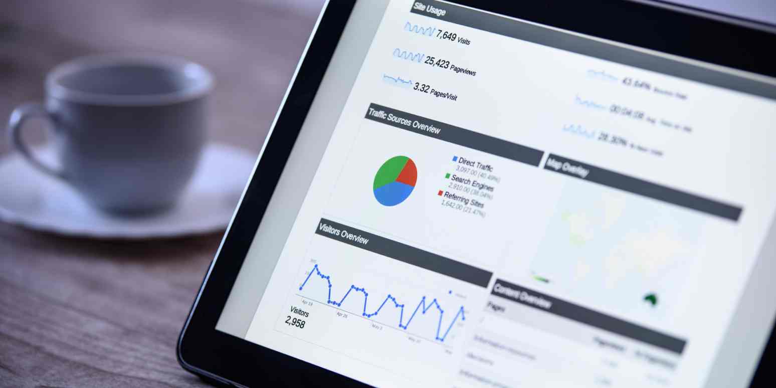 A hero image of a laptop with a cup of coffee next to it, with data analytics / charts on the screen
