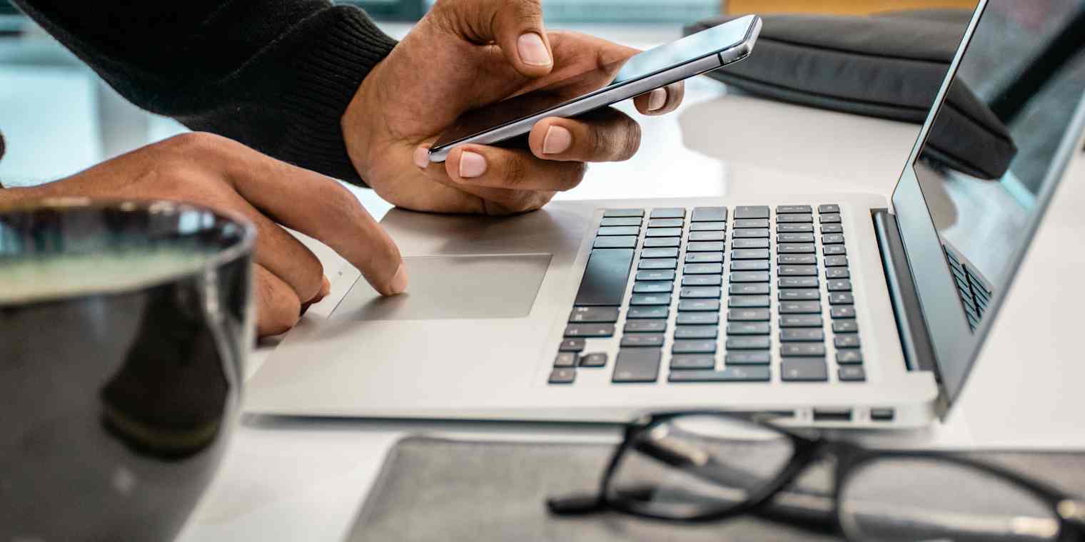 close up photo of hands with phone and laptop