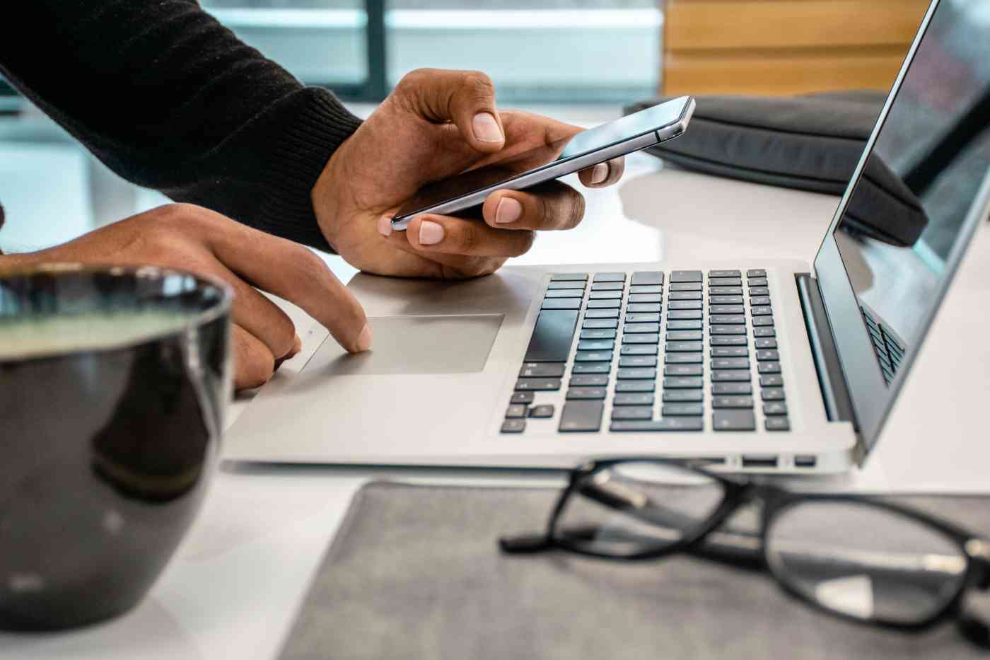 close up photo of hands with phone and laptop