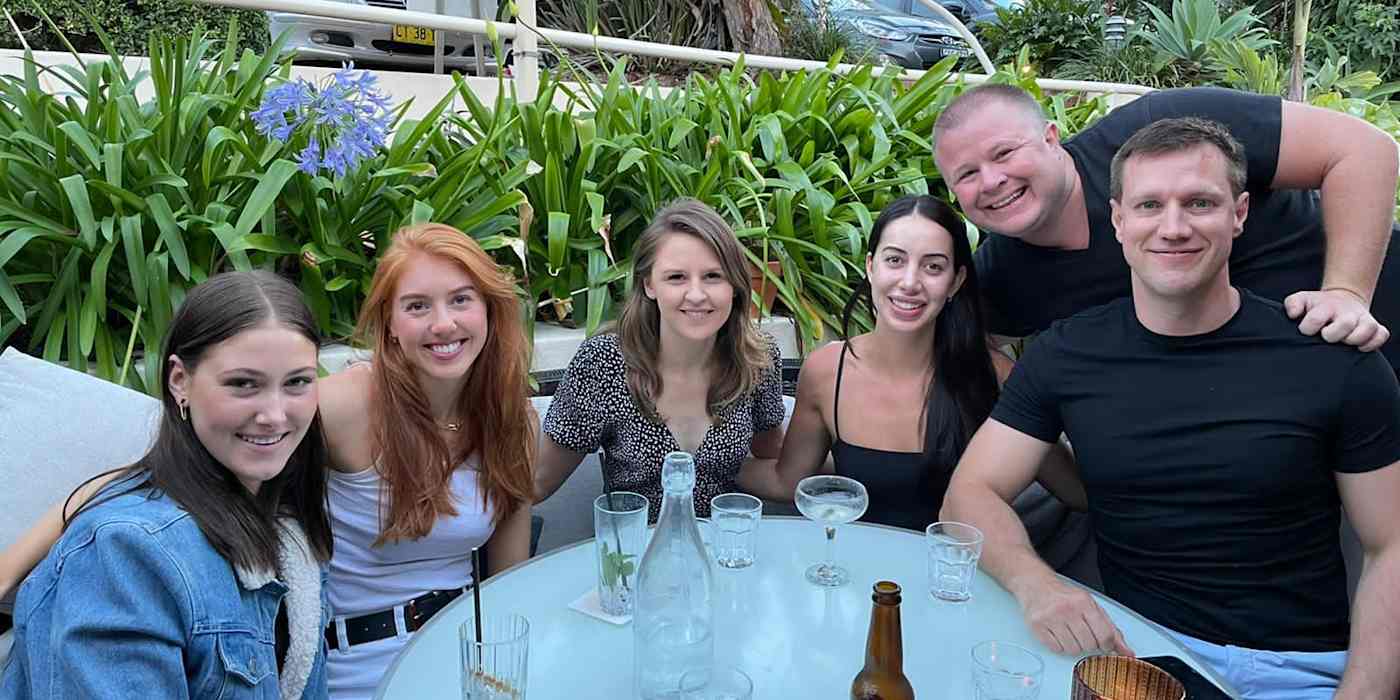 The six members of the Eloquent team sitting together at a table. automation-to-share-leads-with-clients-00-eloquent-team