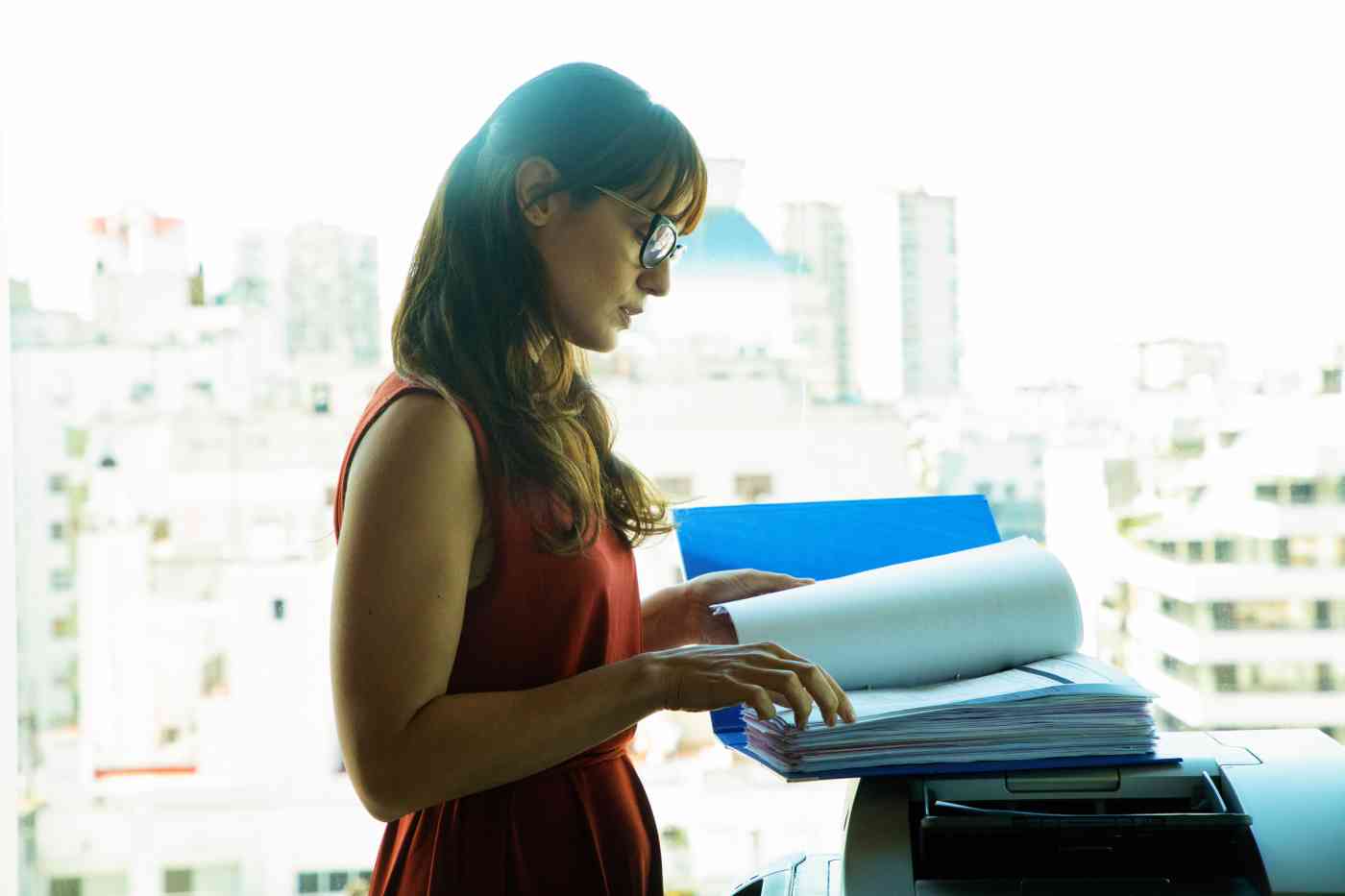 A woman at a copier with a large file.