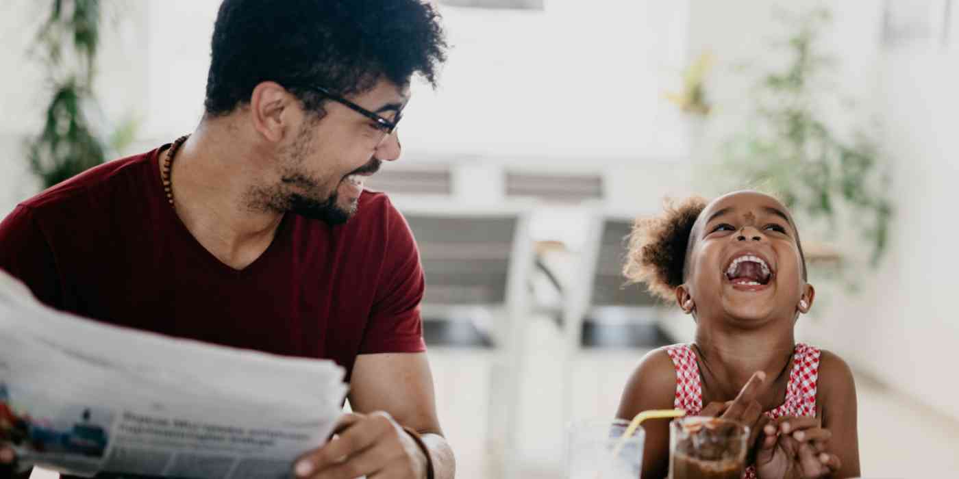 Hero of a man with a newspaper and a young girl laughing next to him