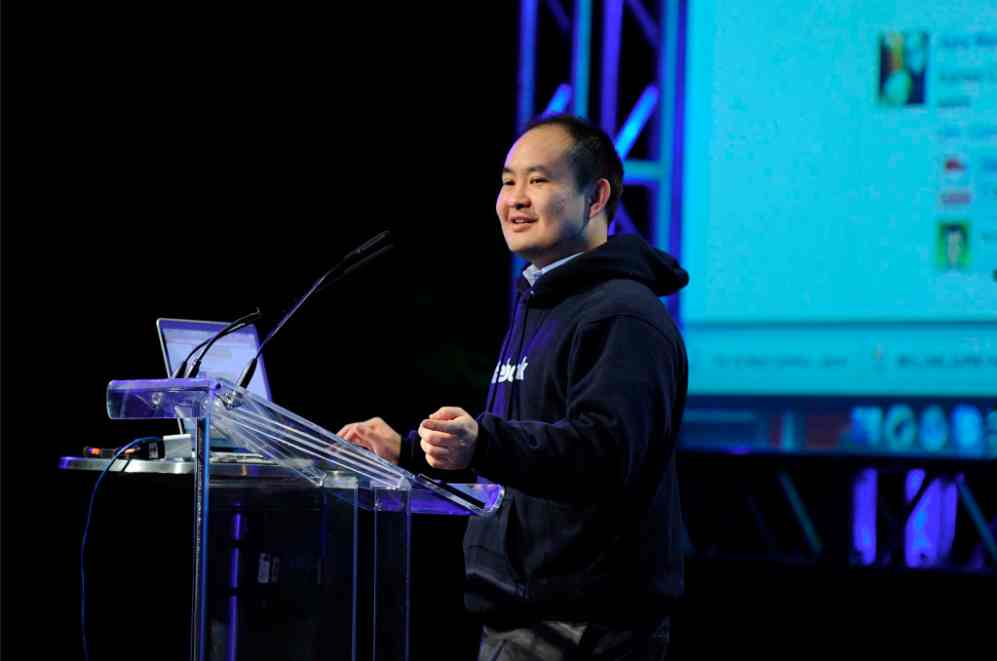 Dennis Yu stands at a podium giving a presentation.