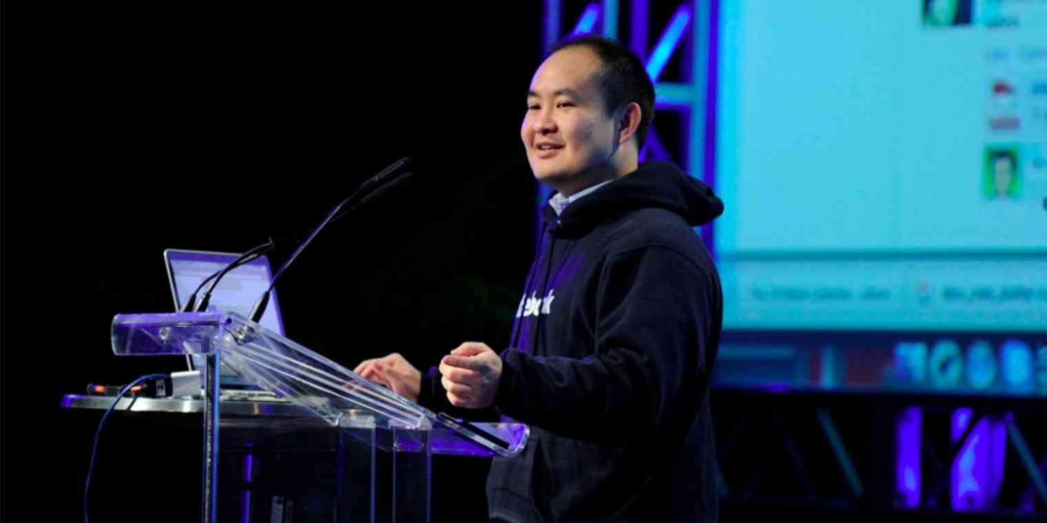 Dennis Yu stands at a podium giving a presentation.