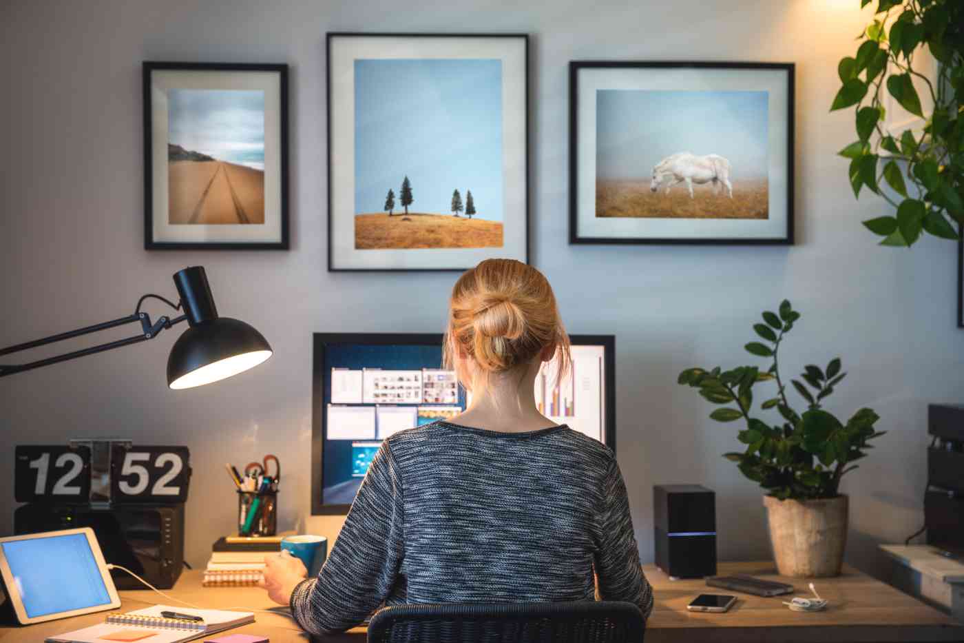 A woman sits at a desk in a home office.