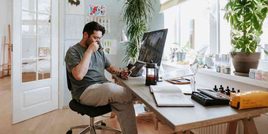 A hero image with a man drinking from a mug while looking at his phone at his desk