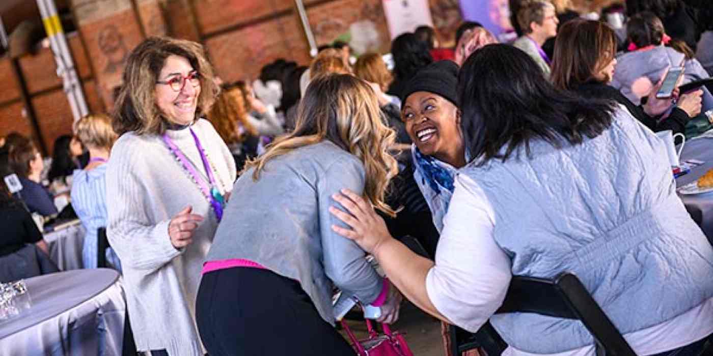 Hero image of women at an event, talking to each other with lots of excitement