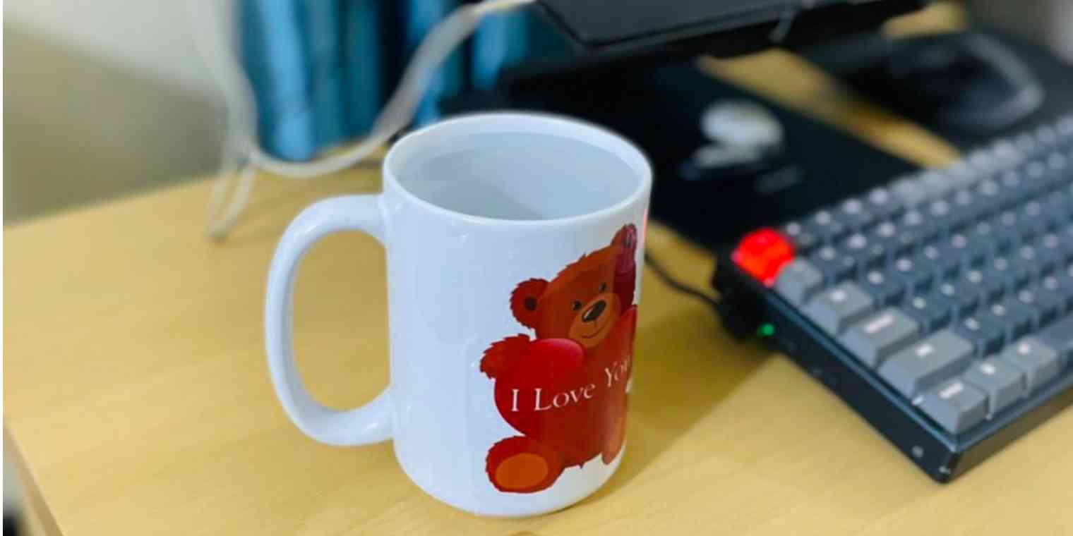 A mug of warm water next to a computer