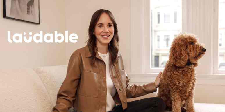 An image of a woman in a brown leather jacket next to a fluffy dog with a Laudable logo overlay