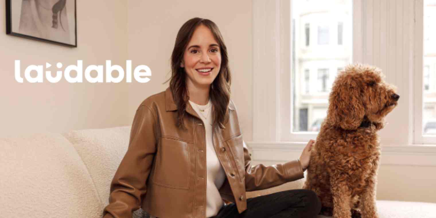 An image of a woman in a brown leather jacket next to a fluffy dog with a Laudable logo overlay