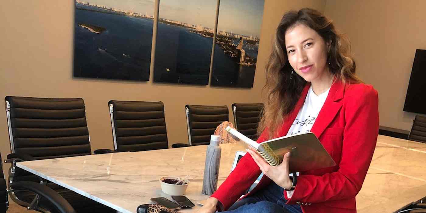 hero image of Vanessa Santos sitting on a conference room table, holding a notepad