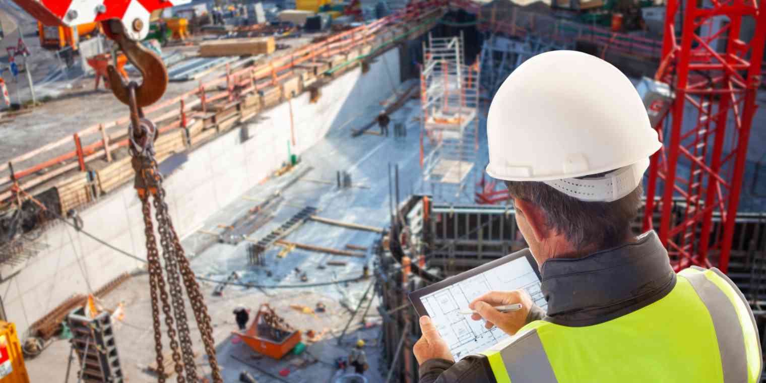 A male construction worker looks over a large building site.