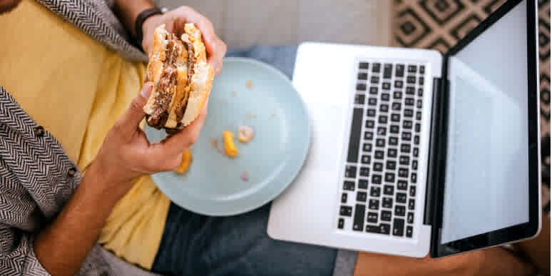 Person eating food or lunch by a computer hero image