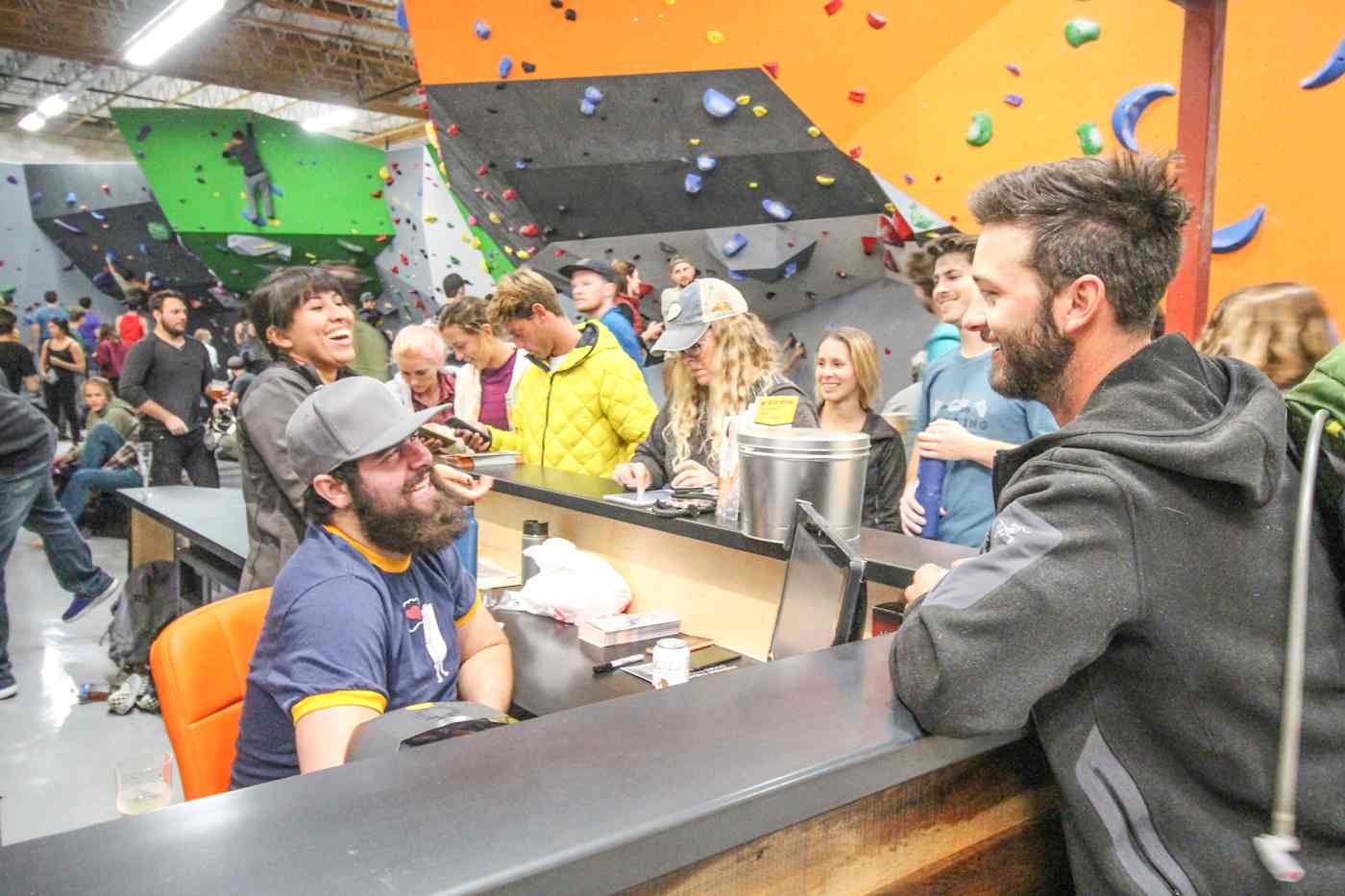 A group of people smiling and laughing at an indoor climbing gym.