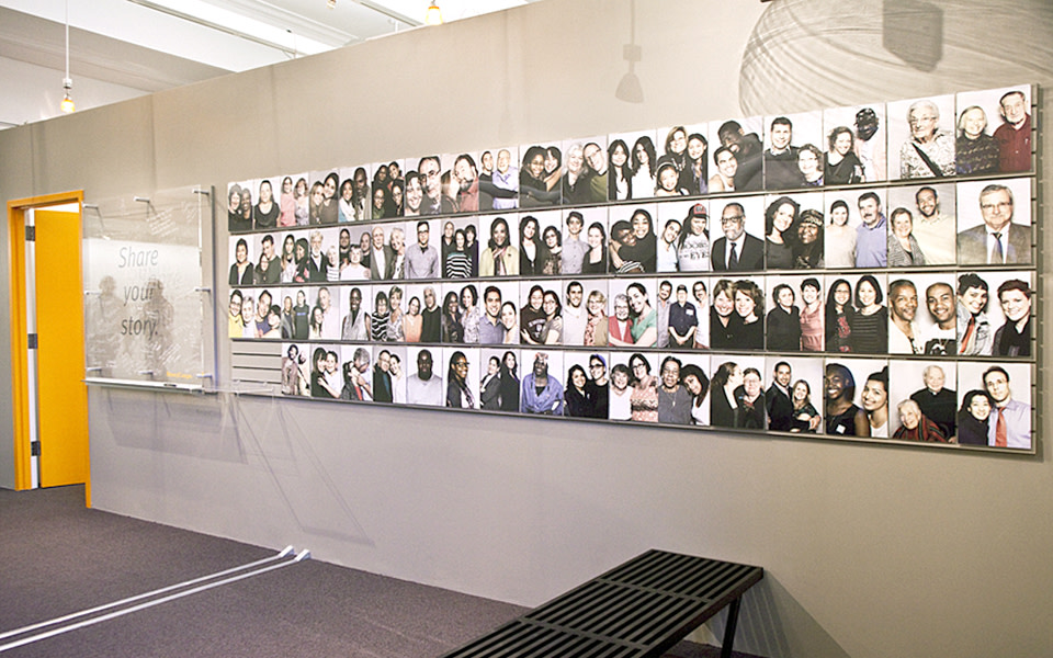 A wall in the StoryCorps office with about 50 photos of people.