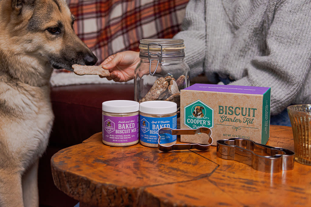 A dog eating a biscuit next to a product bundle