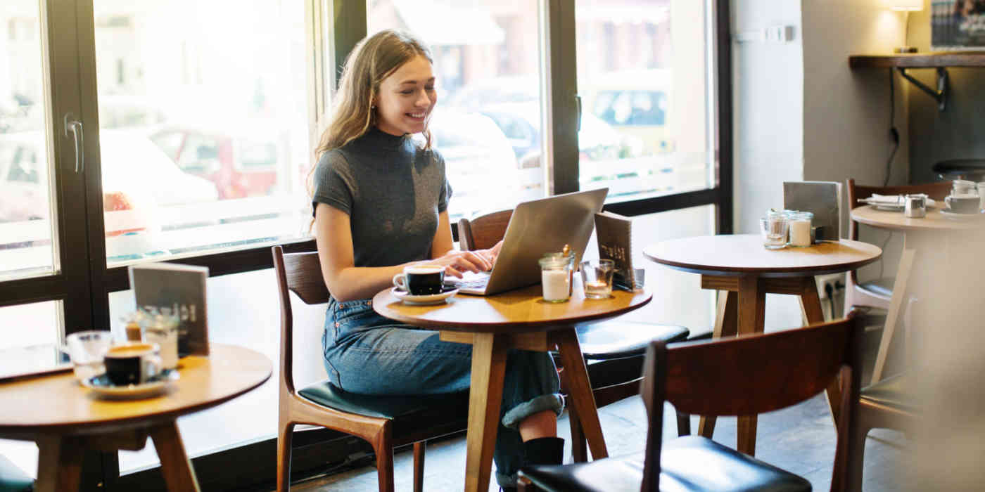 A hero image of a woman at a coffee shop on a computer