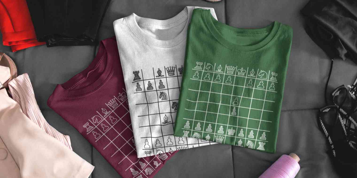 Three folded T-shirts with chess boards printed on the front. 