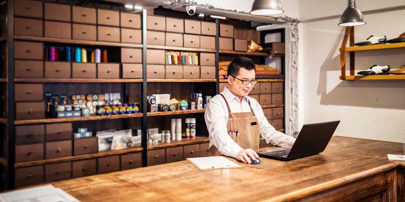 Hero image of a worker at an art supply shop, looking at a computer