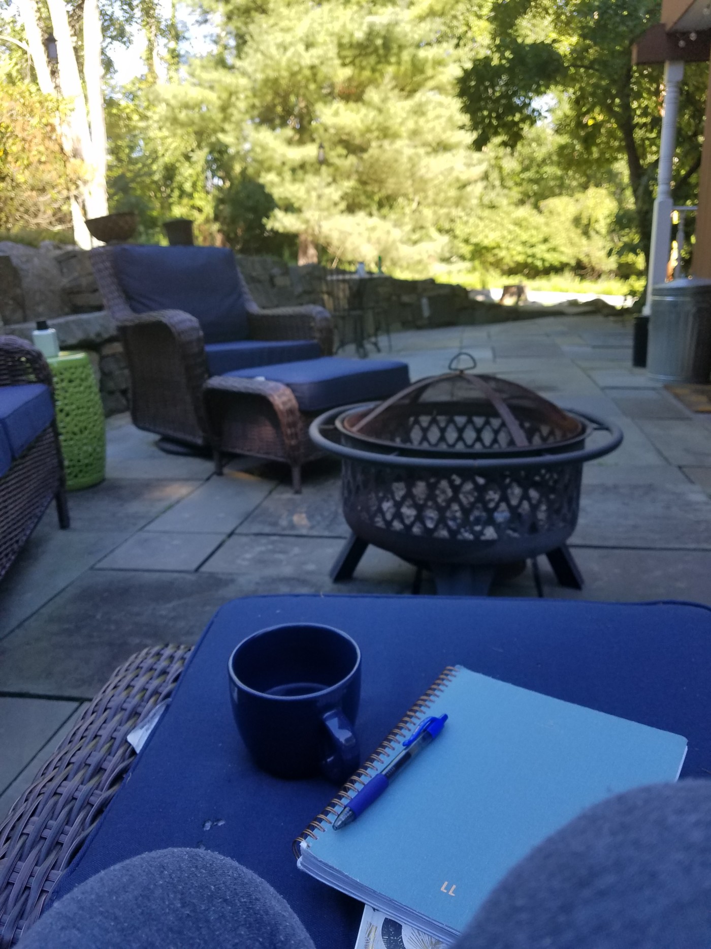 A notebook and mug outside on a patio