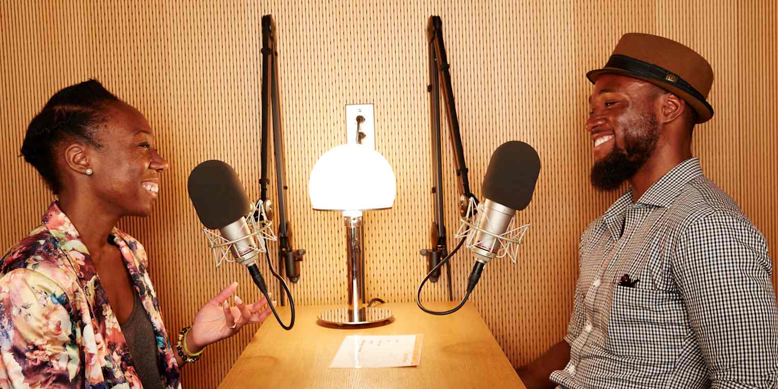 An interview with a woman and a man sitting at a desk with microphones.