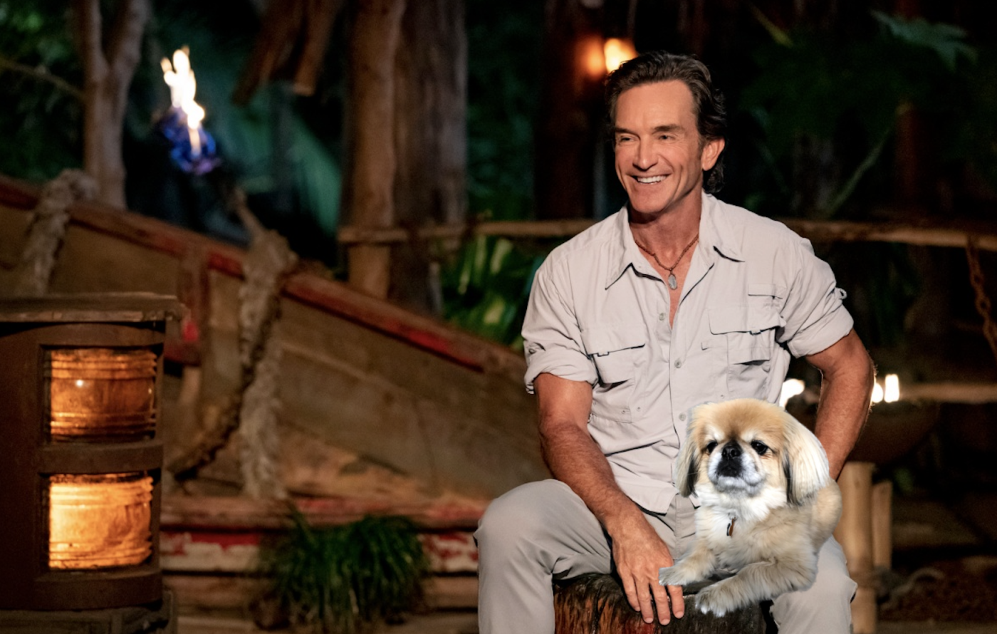 A dog sitting on Jeff Probst's lap