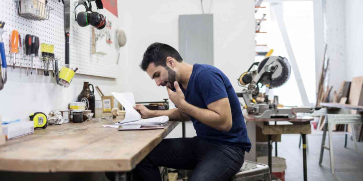 Hero image of someone looking at paperwork at a desk with tools