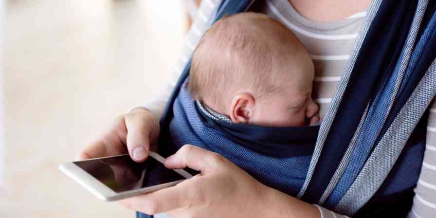 A hero image of a woman holding a baby and writing on a phone