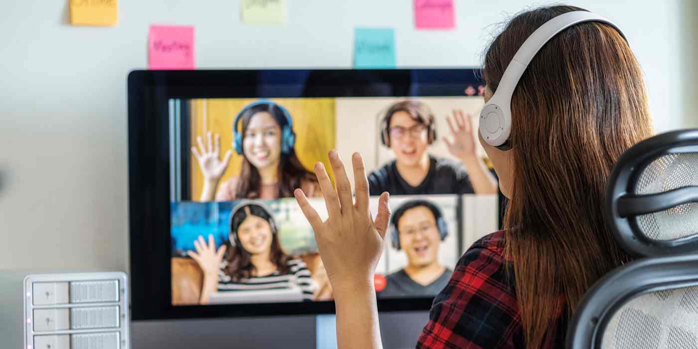 A hero image of a woman waving to four other people (also all waving) on a video call