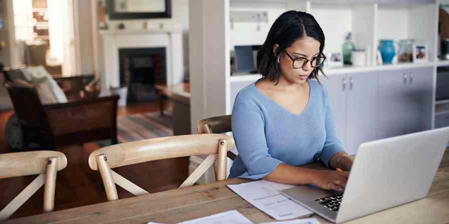 Hero image of a woman at a computer in her kitchen