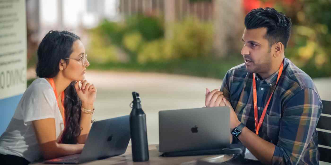 Hero image of two Zapier team members talking to each other over computers, with lanyards around their neck