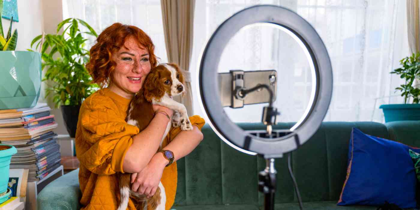 Hero image of an influencer (a woman holding a dog with a ring light)