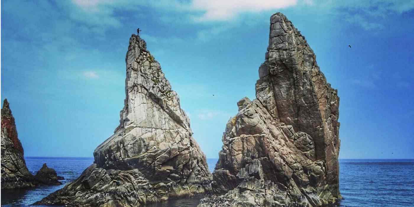 A hero image of giant rocks jutting out of the ocean