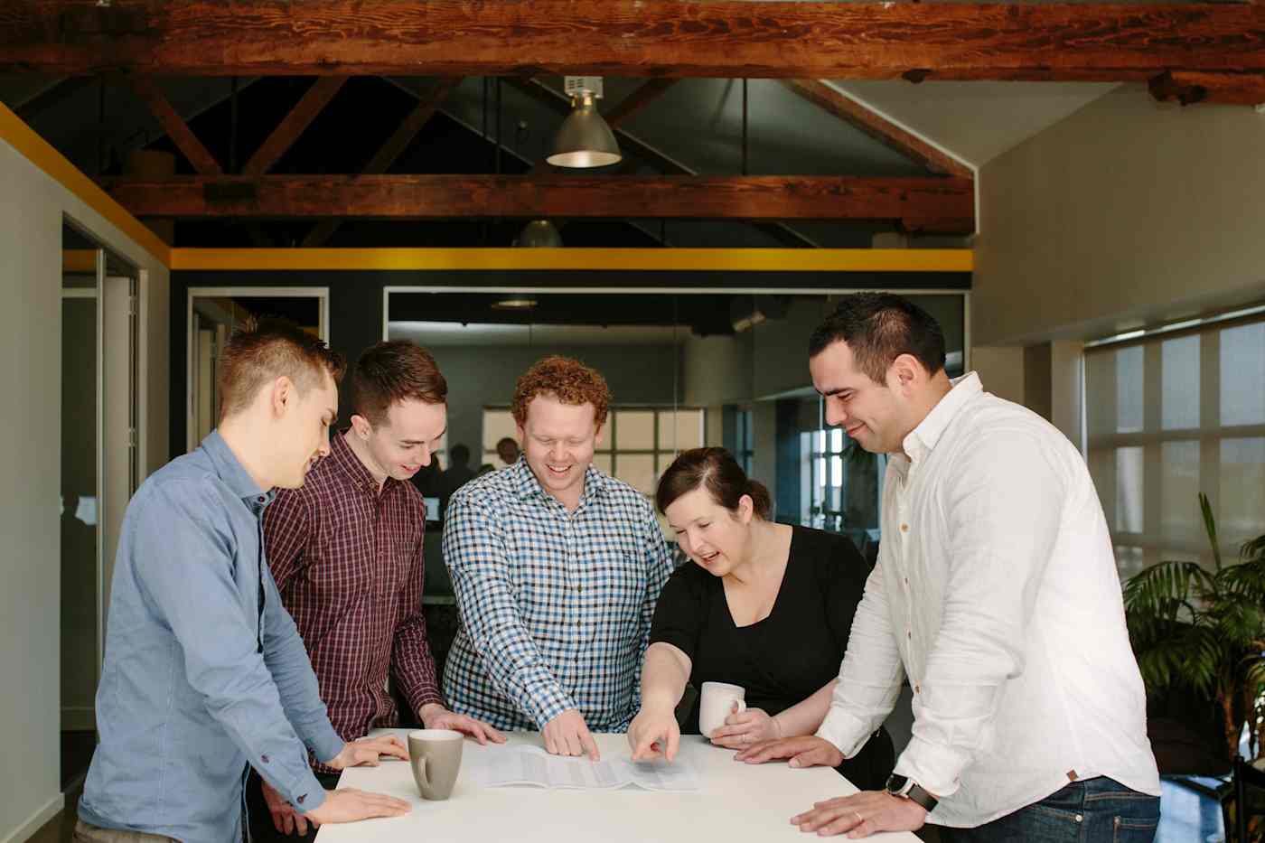 A group of people from the Arlo team stand around a table reviewing a document.