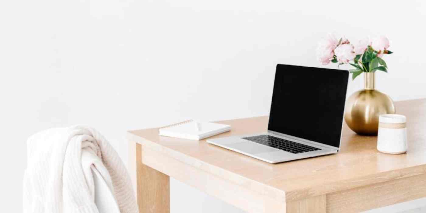 Hero image with a picture of a laptop on a modern desk, with a sweater over the chair