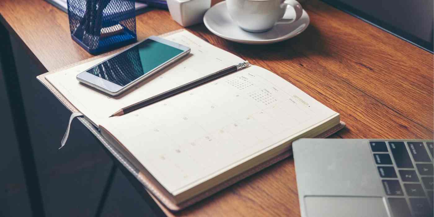 Hero image of a paper calendar on a desk with a computer