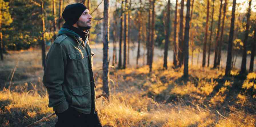 Hero image of a man in a beanie walking through the woods