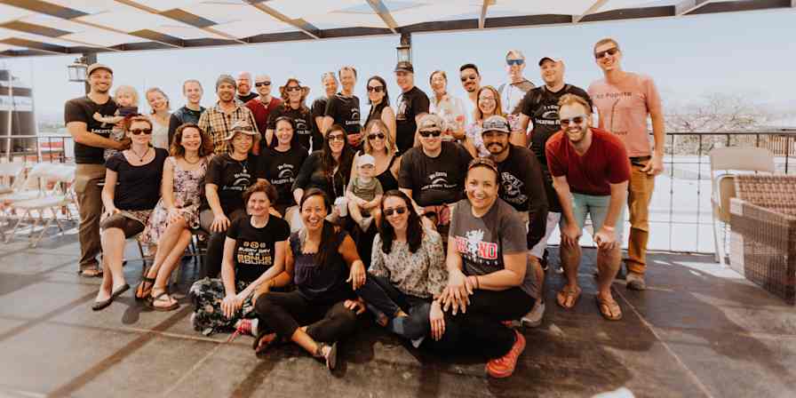 Hero image with a big group of people posing for a picture on a deck