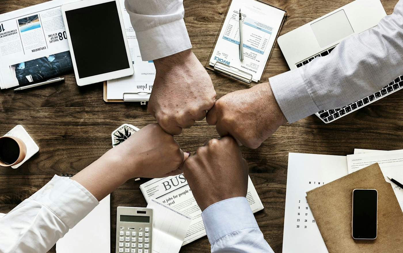 Four fists touching over desk