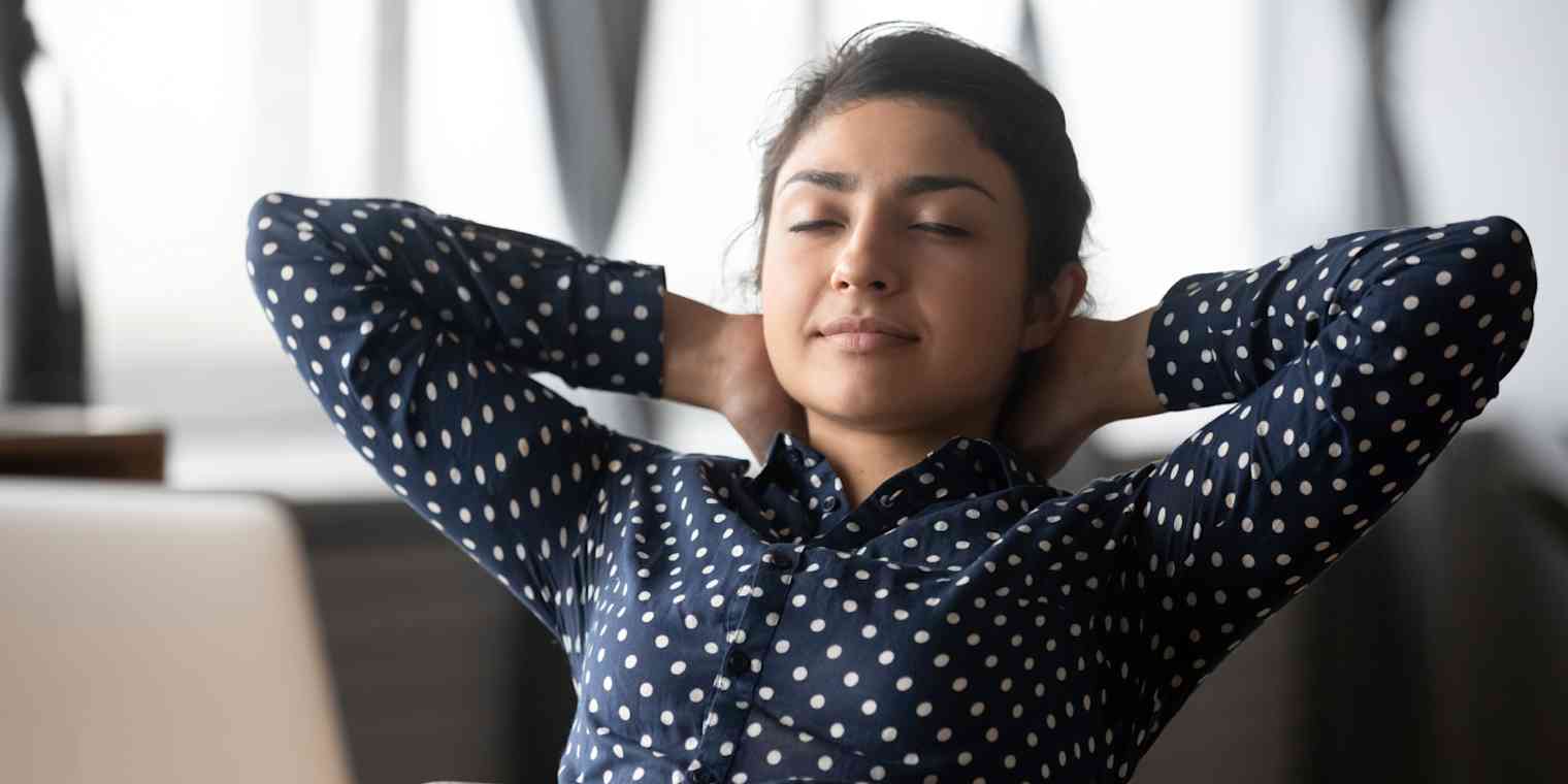 None Hero image of a woman leaning back in a chair with her arms behind her head and her eyes closed