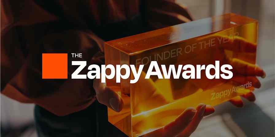 A photo of two hands holding holding an amber, rectangular award with the Zappy Awards logo superimposed over the image