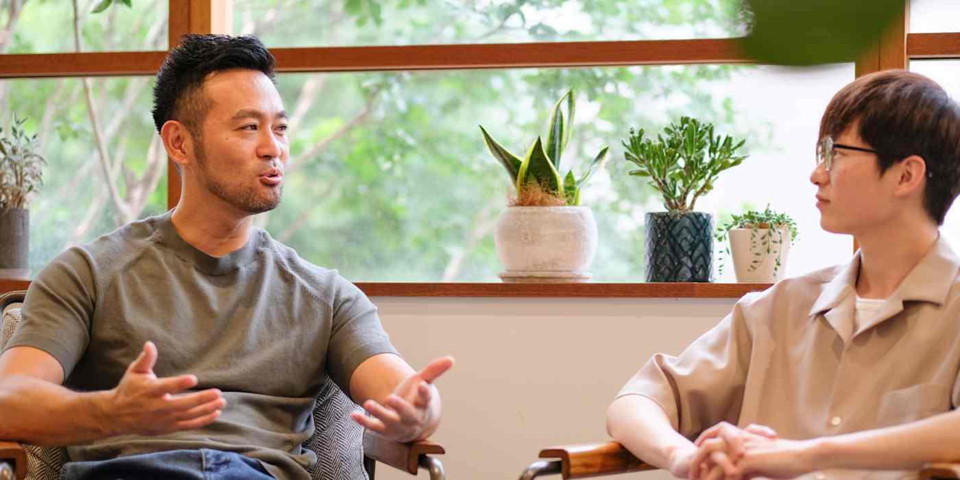 A hero image of two men seated, talking to each other, one of them gesticulating