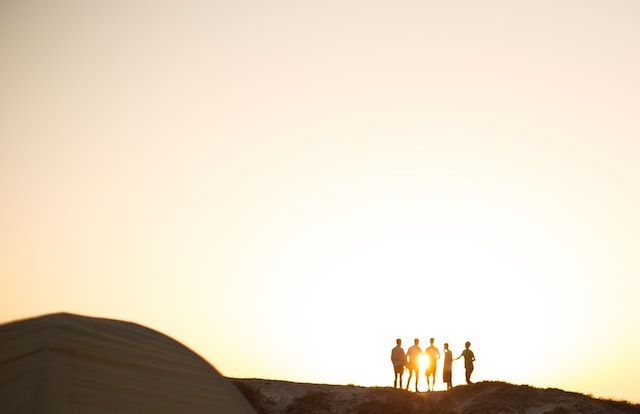 People standing together in the distance with sunset behind them