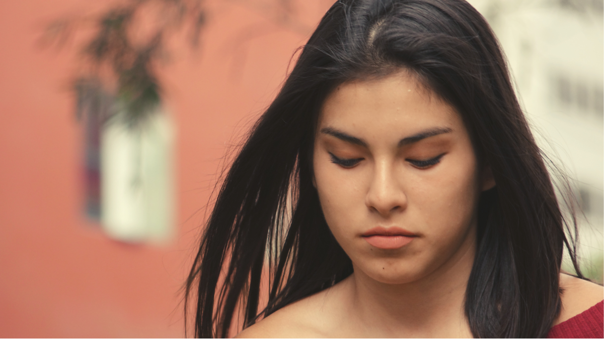 Frowning woman in front of an orange building.