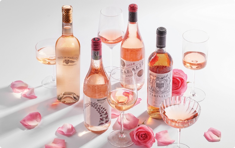 Four bottles of rosé wine with flower petals and glasses