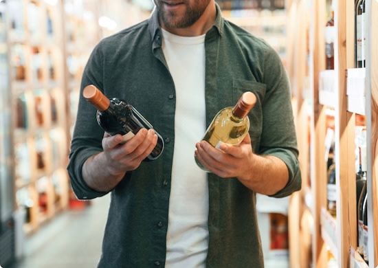 Man comparing two bottles of non-alcoholic wine in a wine store