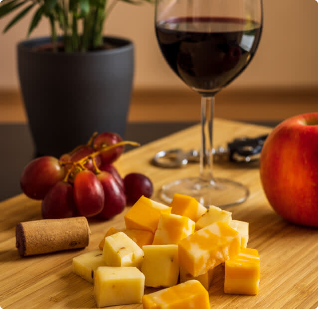 Cubes of cheese, grapes, and an apple alongside a glass of Malbec wine on a table