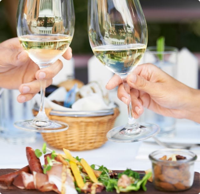 Two hands toasting with glasses of Sauvignon Blanc wine paired with prosciutto