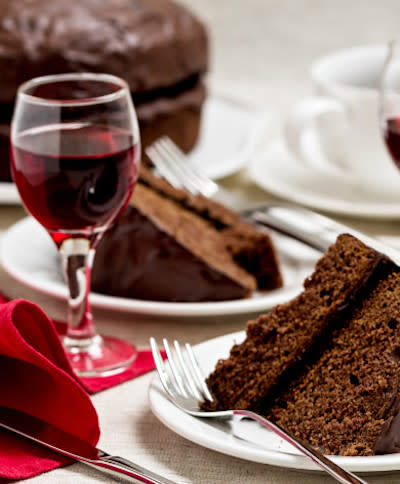 A glass of red wine next to slices of chocolate cake